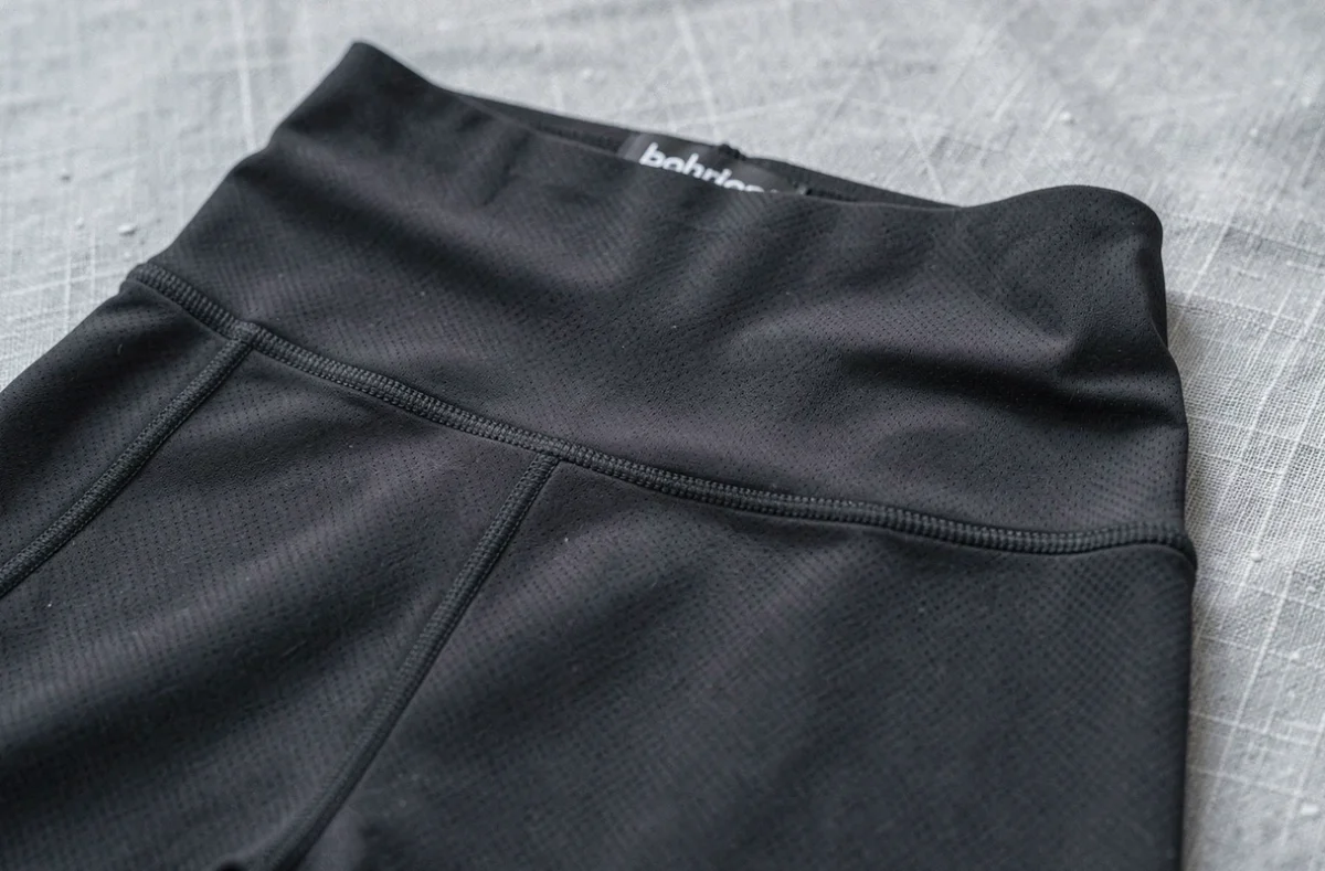 Gros plan sur la texture et la ceinture haute d'un legging minceur en tissu de compression noir
